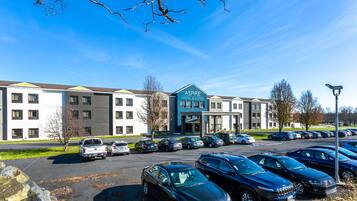 A hotel with multiple parking spaces and a clear blue sky.