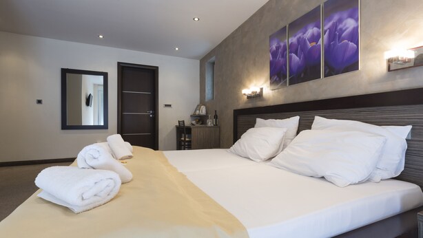 A modern hotel room with a large bed, a bedside table, a mirror, and artwork on the wall. - Villa Mystique (Belgrade)