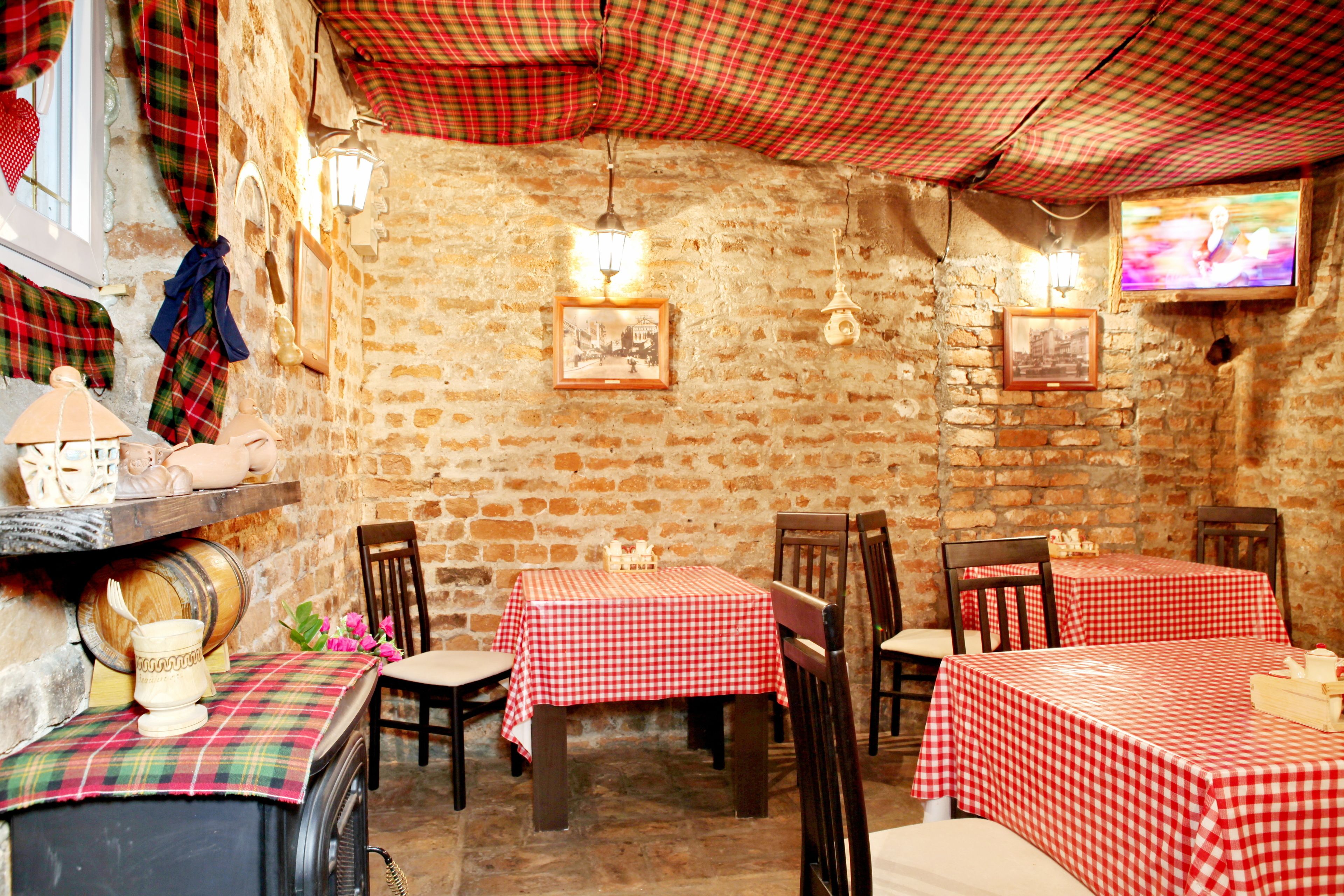Un restaurant rustique aux murs de briques, aux meubles en bois et aux nappes à carreaux rouges et blancs.