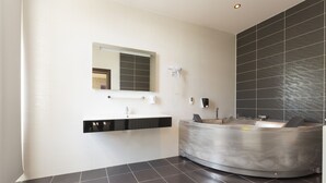 A modern bathroom with a curved vanity, a large mirror, and a black tiled wall. - Villa Mystique (Belgrade)