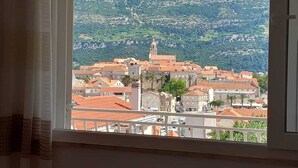 A view from a window overlooking a town with red-roofed buildings and a mountain in the background. - Accommodation Drasko (Korcula)