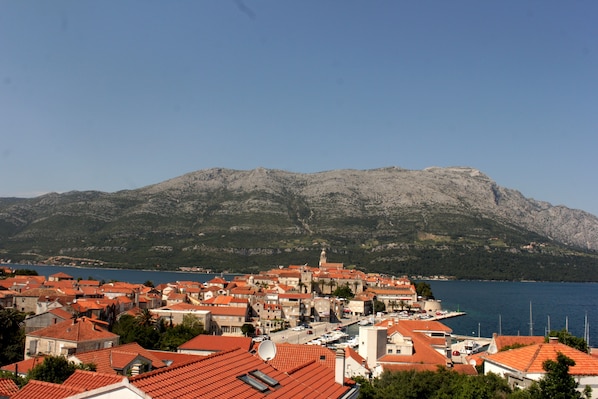 A coastal town with red-roofed buildings, a marina, and a mountain in the background.