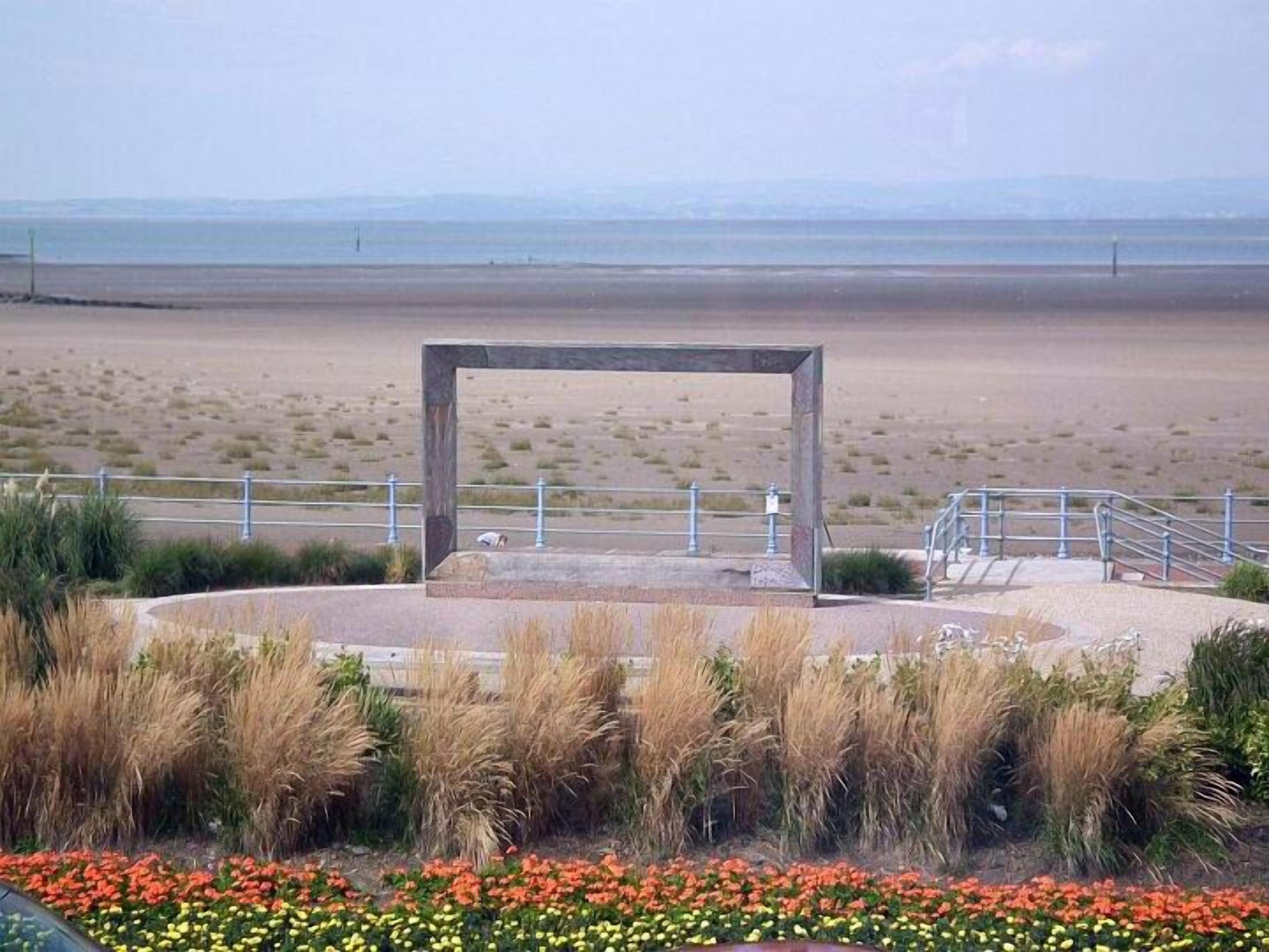 A landscaped area with a central structure, surrounded by a railing and a flower bed.