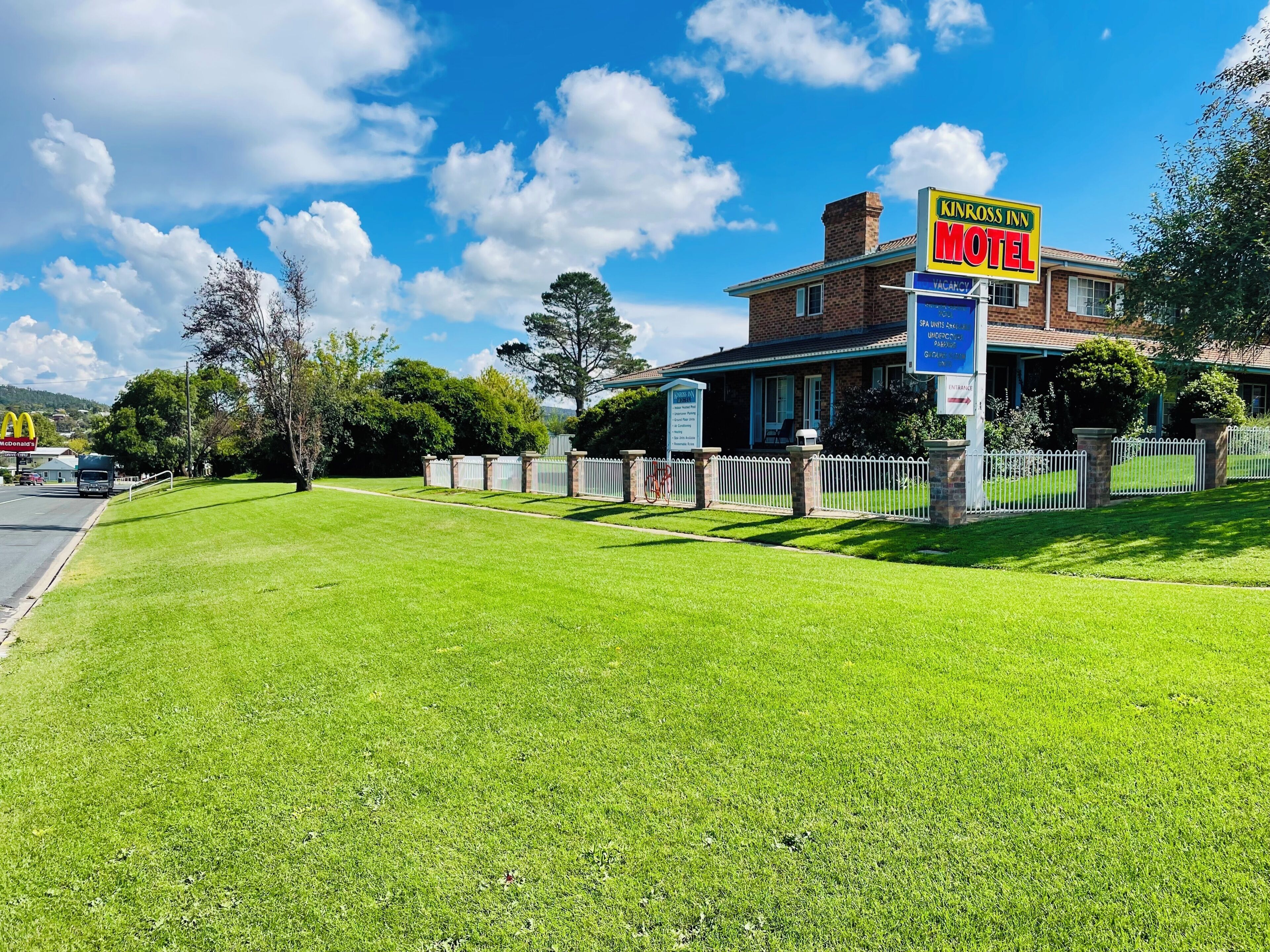 A motel with a signboard, a fenced yard, and a McDonald's visible in the background.
