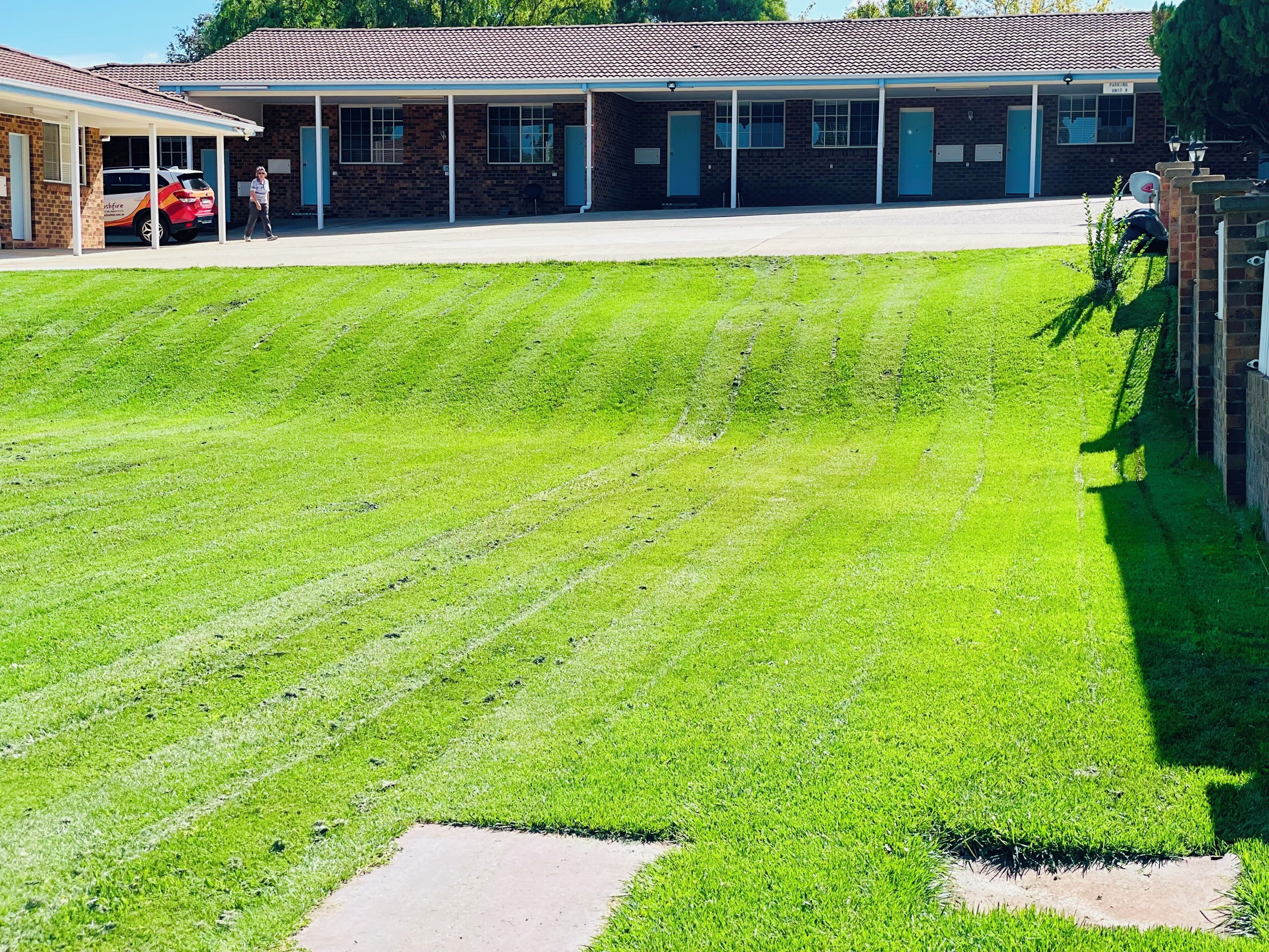A building with a covered parking area and a well-maintained lawn.