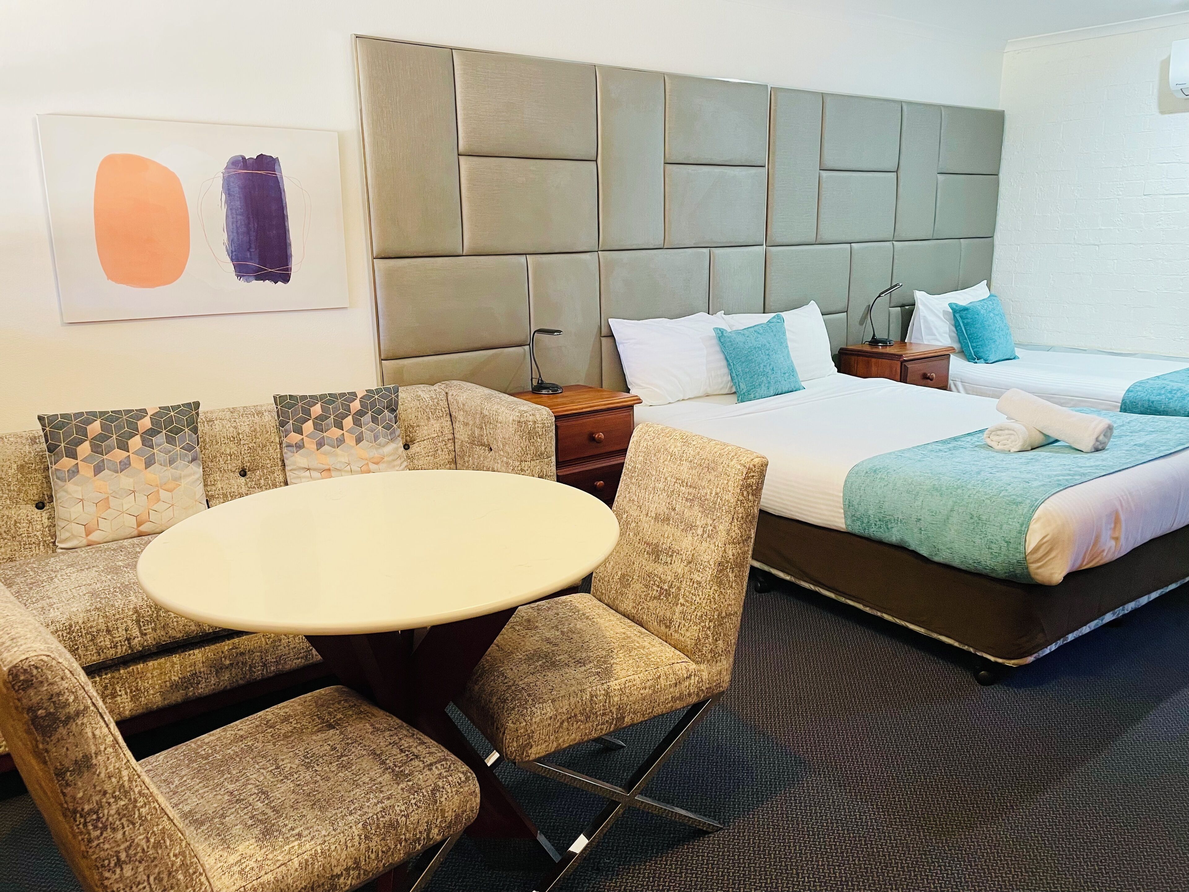 A hotel room with a bed, a round table, and a sofa set.