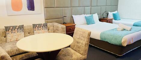A hotel room with a bed, a round table, and a sofa set.