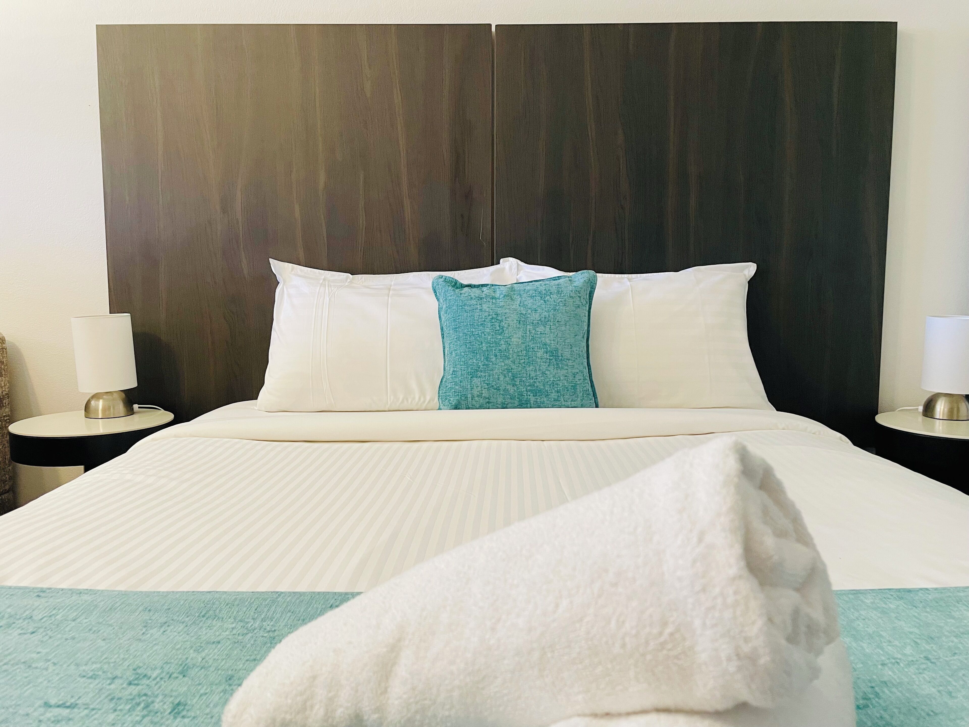 Une chambre d’hôtel avec un grand lit, deux tables de chevet et une tête de lit en bois foncé.