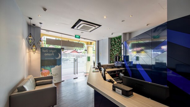 A modern reception area with a sofa, a reception desk, and a wall with a geometric pattern.