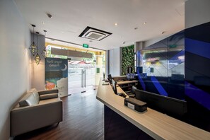 A modern reception area with a sofa, a reception desk, and a wall with a geometric pattern.