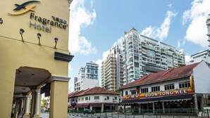 A hotel named 'Fragrance Hotel' with a yellow facade, a sign for 'BOON TONG KEE' restaurant, and modern high-rise buildings in the background.