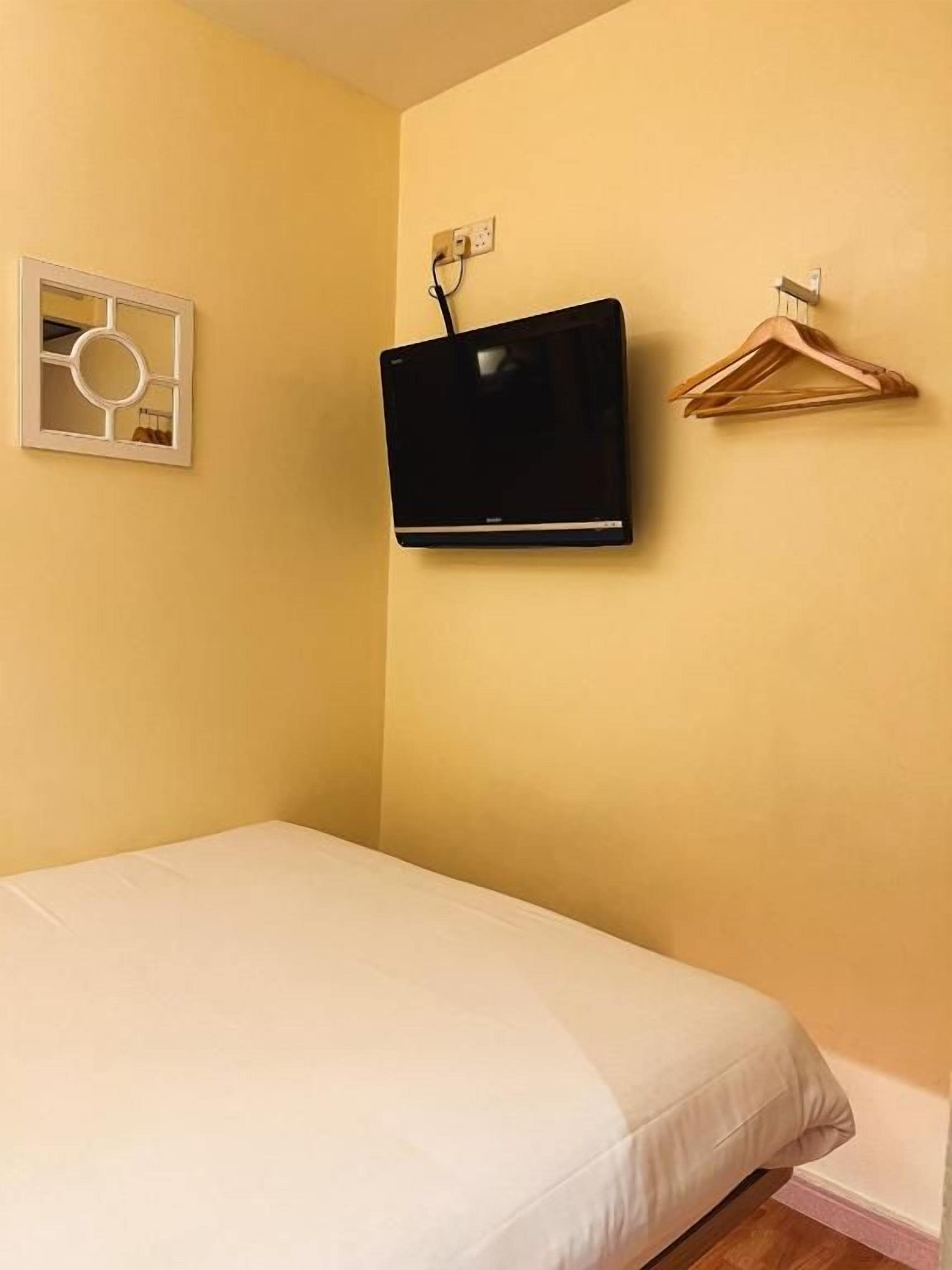 A room with a bed, a mounted television, and a wall-mounted heater.