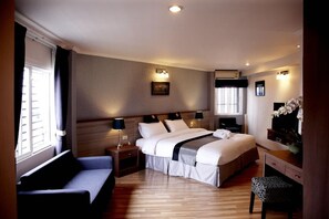 A hotel room with a large bed, bedside tables, a desk, a chair, and a window with curtains. - Poste 43 Residence (Bangkok)