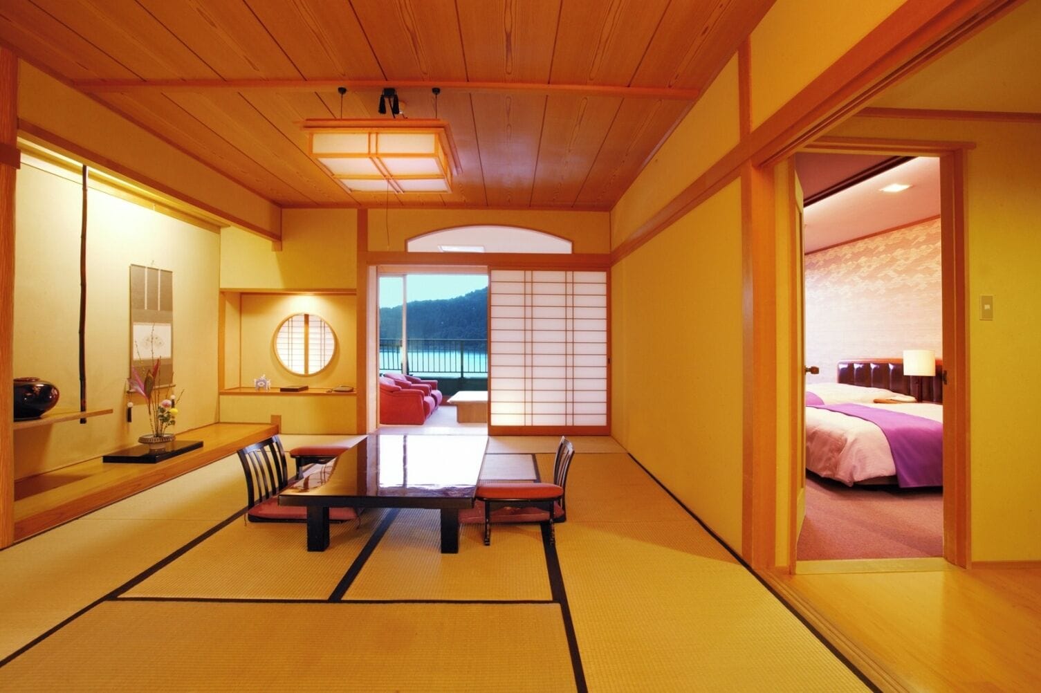 A traditional Japanese-style room with tatami flooring, a low table, and a view of the sea.