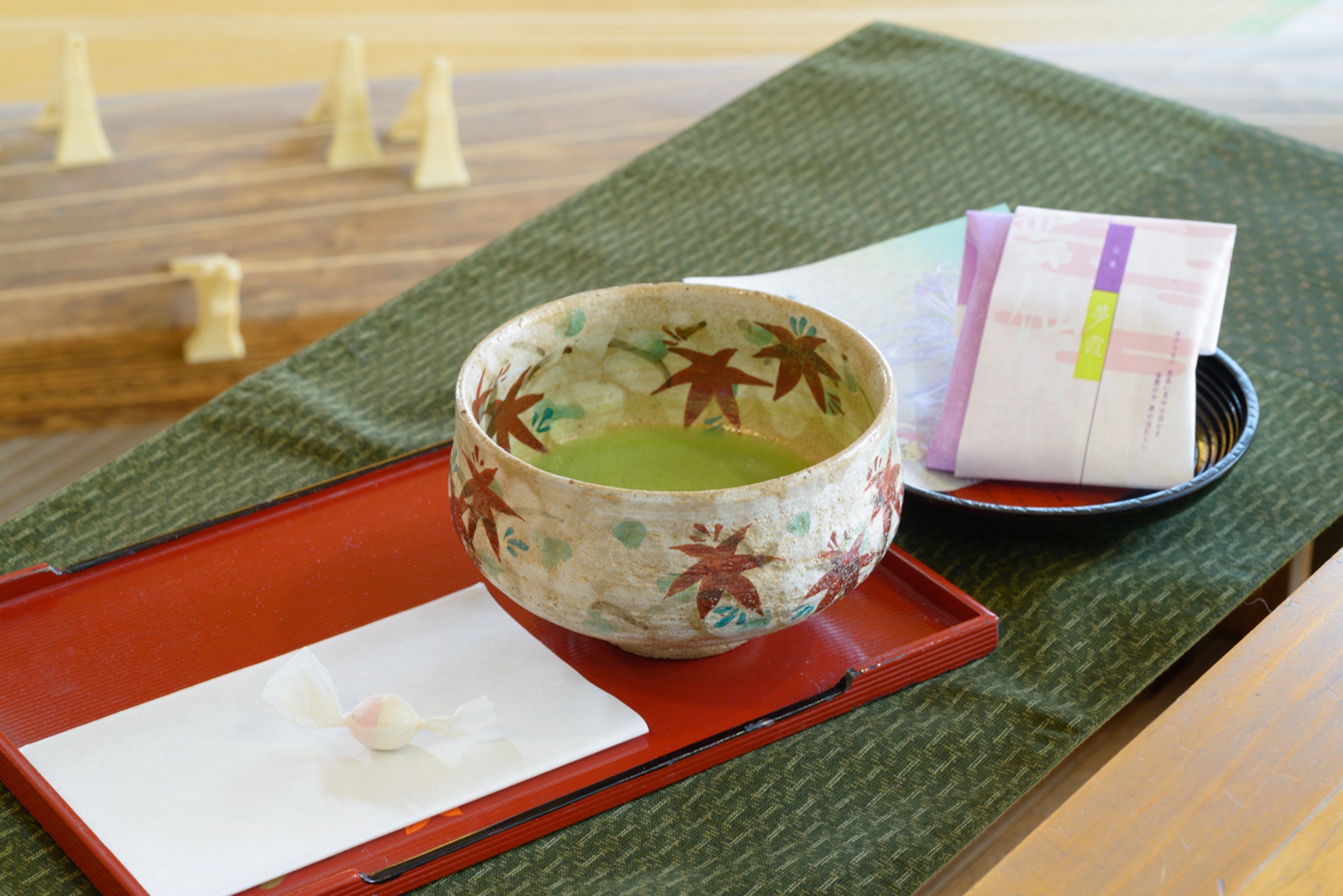 A traditional Japanese tea set on a tatami mat with a wooden tray, a ceramic bowl, and a white paper with a tea bag.