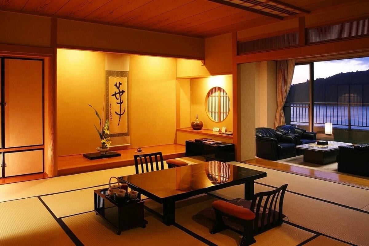 A traditional Japanese-style room with tatami flooring, a low table, and seating.