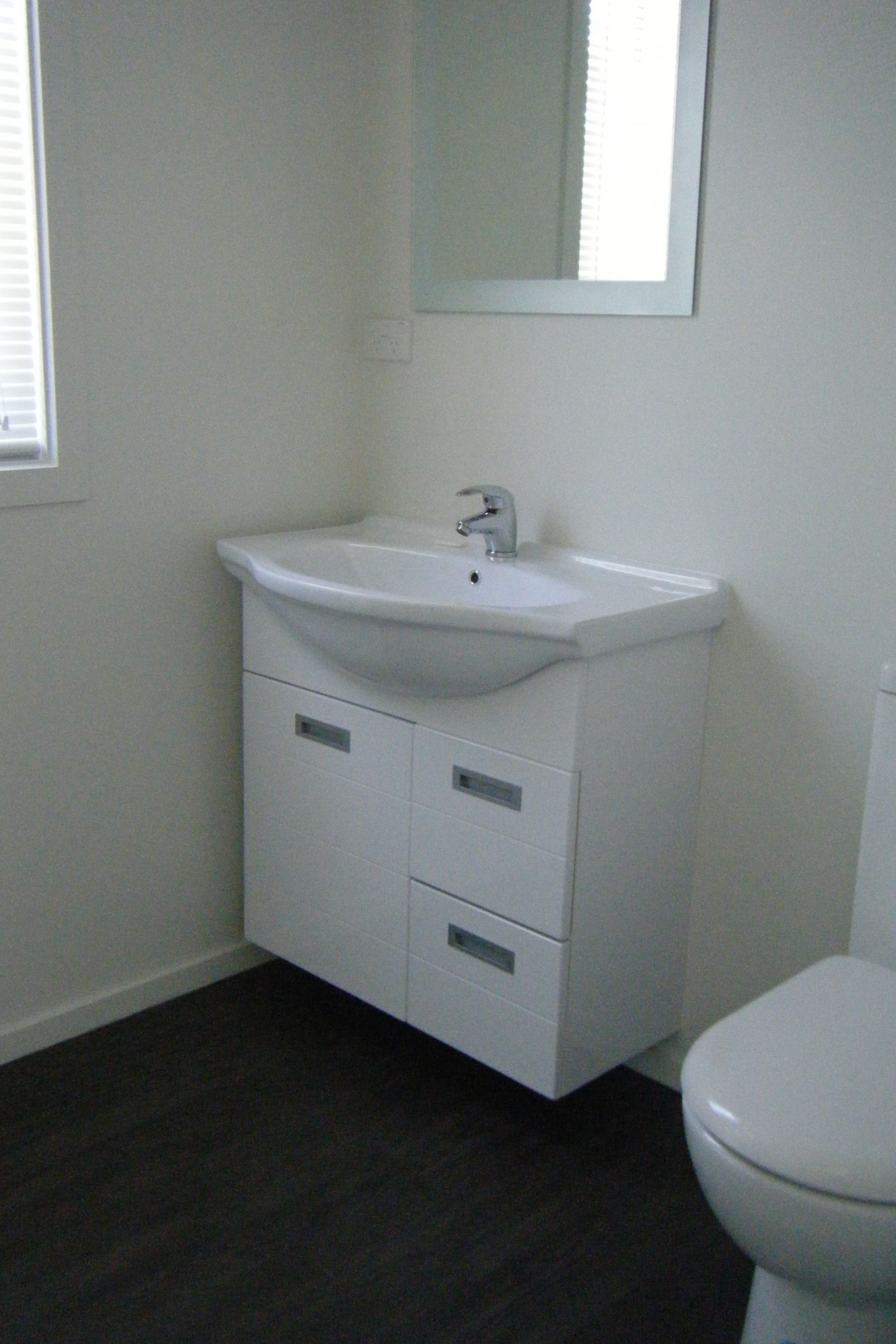 A bathroom with a white sink, mirror, and toilet.