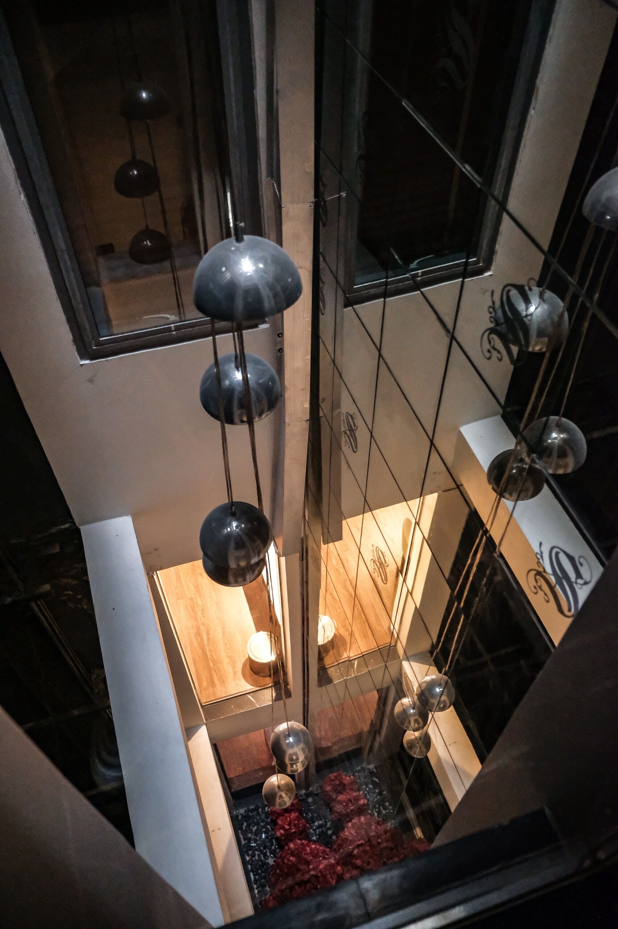 A modern interior with hanging spherical light fixtures, a wooden floor, and a glass partition.