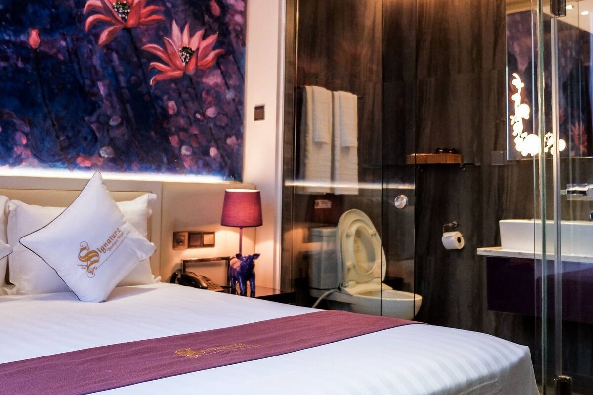 Una habitación de hotel moderna con una cama grande, cabina de ducha de vidrio y un mural en la pared.