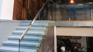 Un bâtiment moderne doté d’un escalier en verre, de lambris en bois et d’une pièce visible où se trouve une moto.