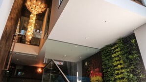 Un intérieur moderne agrémenté d’un escalier, d’un luminaire décoratif et d’un présentoir à plantes fixé au mur.