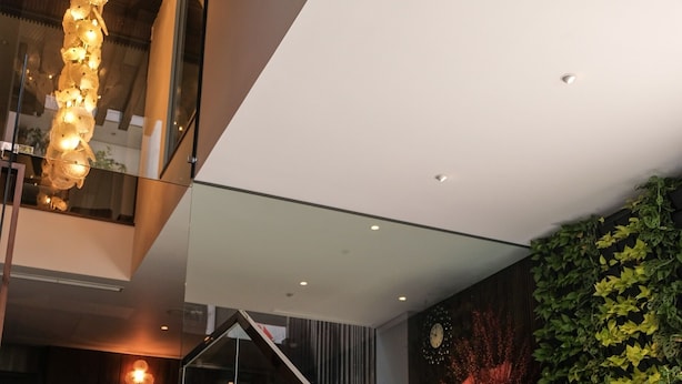Un intérieur moderne avec un escalier, un luminaire décoratif et un mur végétal.