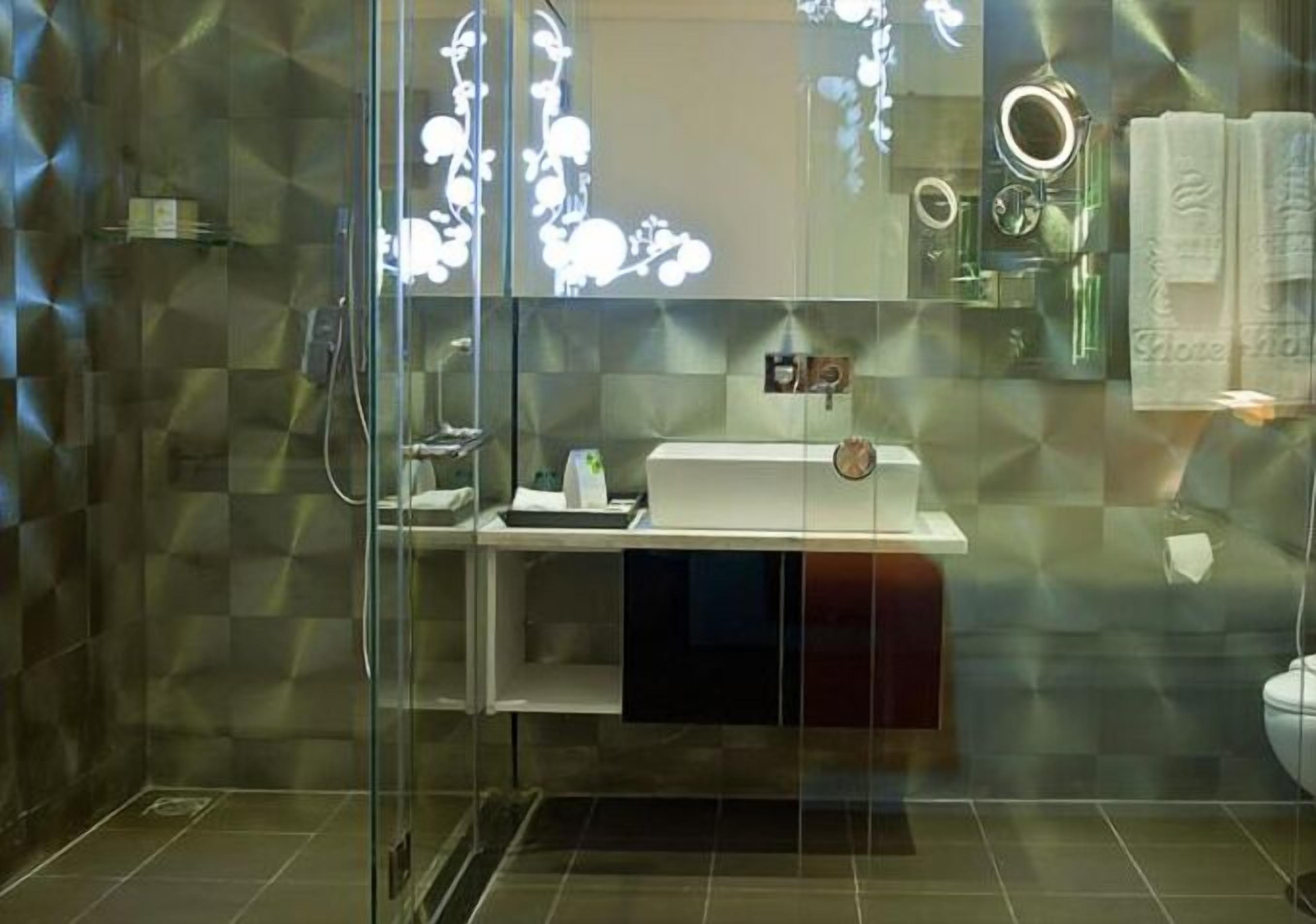 Ein modernes Badezimmer mit einer Duschkabine aus Glas, einem Waschtisch mit Spiegel und einer Toilette, die durch das Glas sichtbar ist.
