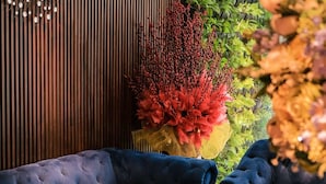 Un espace de détente moderne avec un canapé bleu, une horloge murale décorative et un jardin vertical.