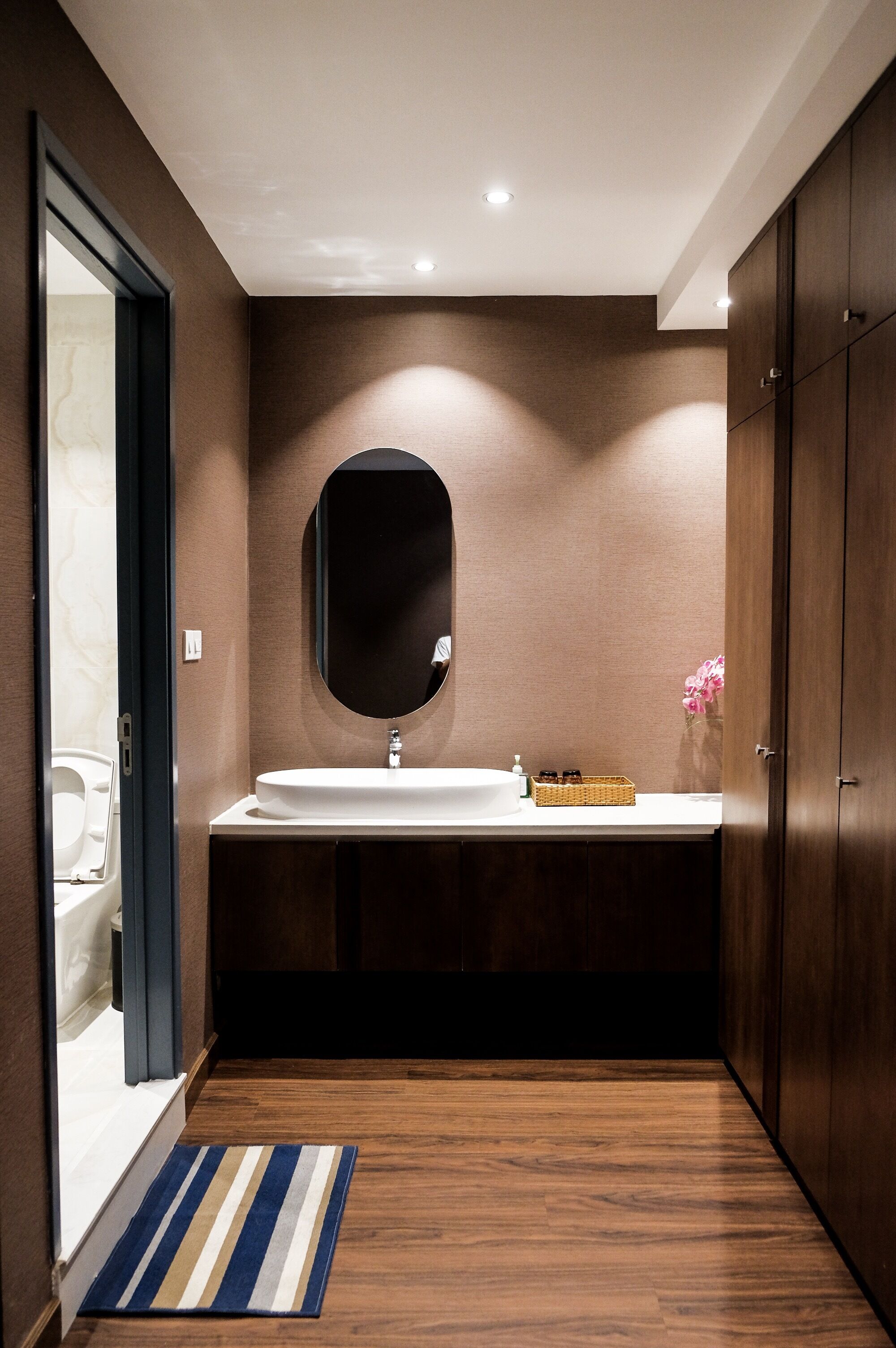 Une salle de bain moderne avec un plancher en bois, un lavabo blanc et un grand miroir.