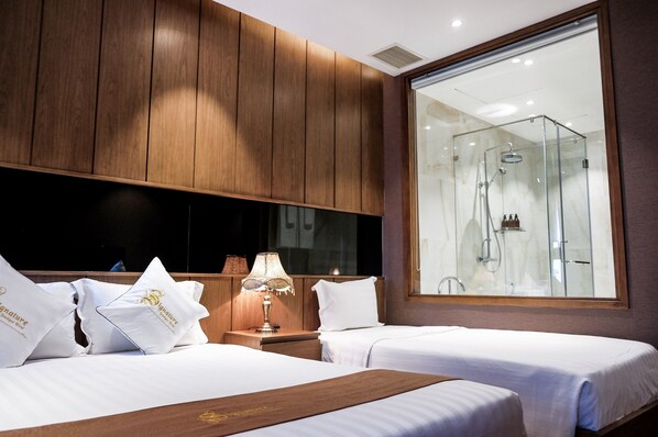 A hotel room with two beds, a large mirror, and a glass-enclosed shower.