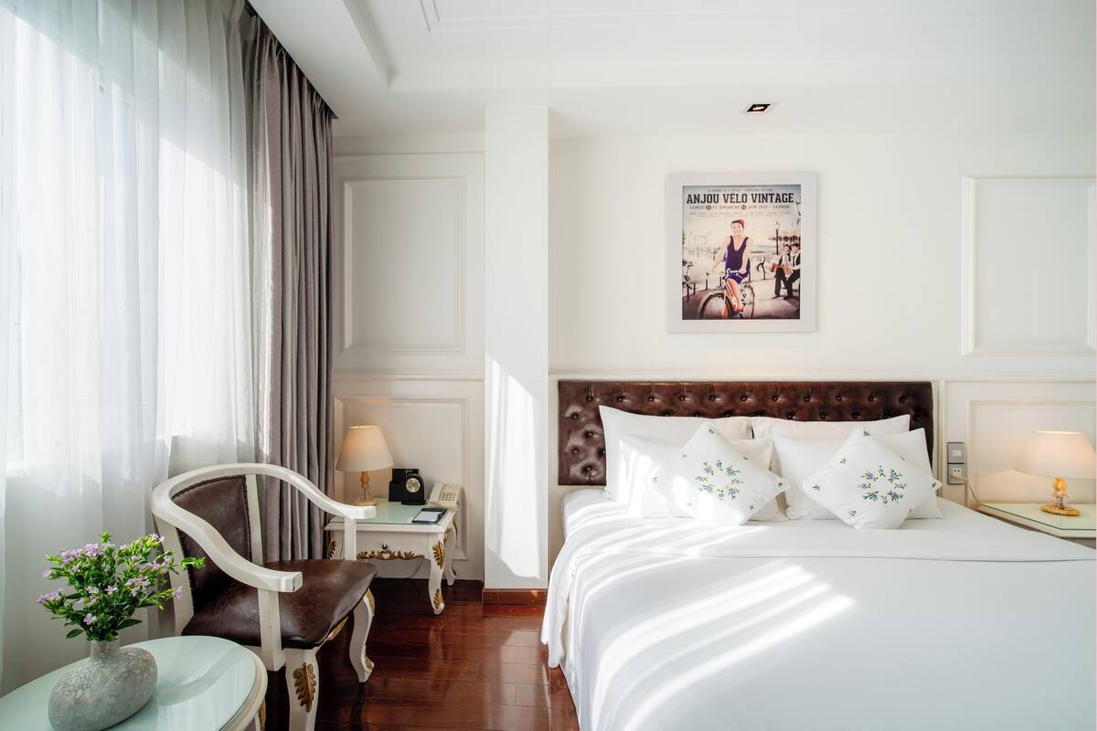 Een hotelkamer met een groot bed, een stoel, een bureau en een poster aan de muur.