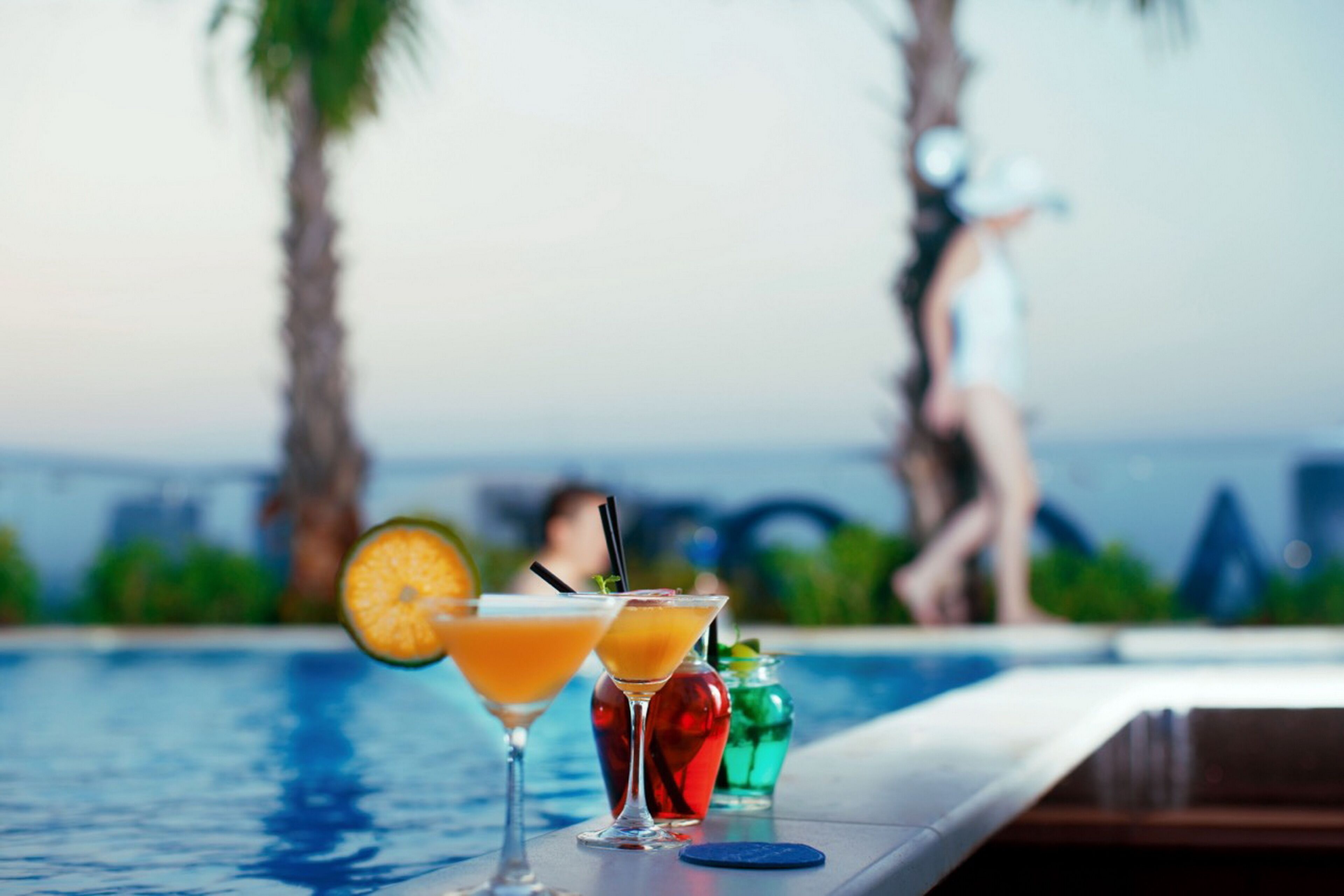 A poolside bar with drinks and a person in the background.