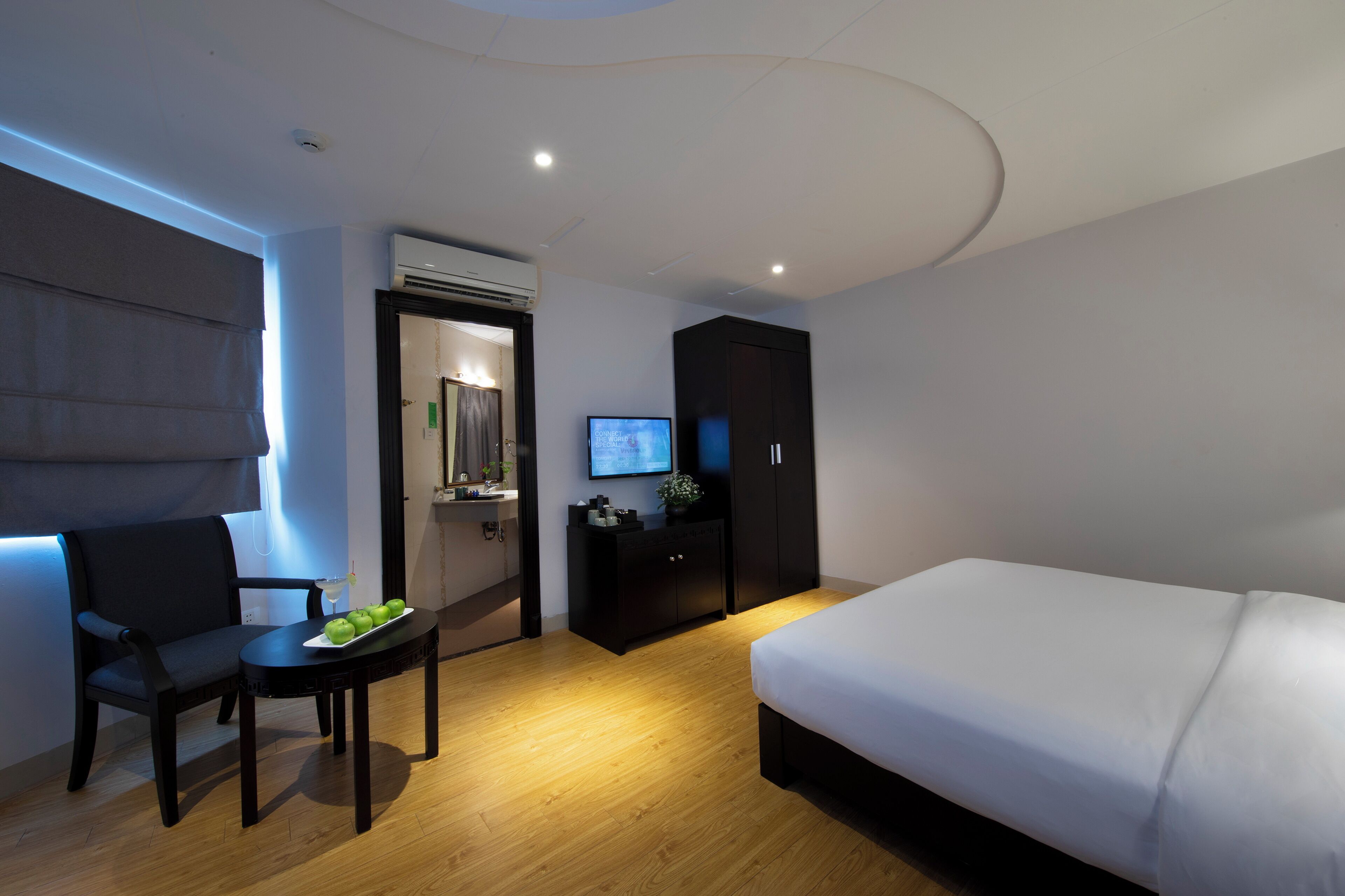 Une chambre d’hôtel moderne équipée d’un lit, d’un bureau avec une chaise, d’une télévision et d’une armoire.