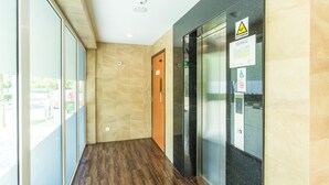 A modern hallway with a wooden floor, glass walls, and a door with a safety sign.