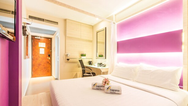 A hotel room with a bed, a desk, a chair, and a bathroom visible through an open door.