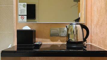 A small kitchenette with a coffee maker, a kettle, and a box on the counter.