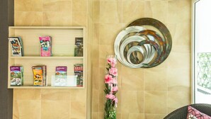 A wall with a shelf displaying books and a decorative metal piece.