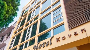 Un hotel con fachada amarilla, grandes ventanales y una tienda de conveniencia 7-Eleven en la planta baja.