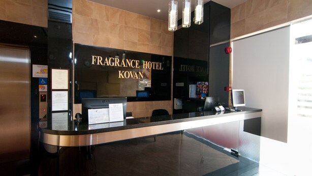 Mostrador de recepción del Fragrance Hotel Kovan, de diseño moderno, con una computadora y una pantalla digital.