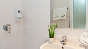 Un baño moderno con lavamanos, espejo, toallero y ducha.