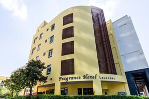 Un hotel de varios pisos con fachada amarilla y un letrero que dice 'Fragrance Hotel Lavender'.
