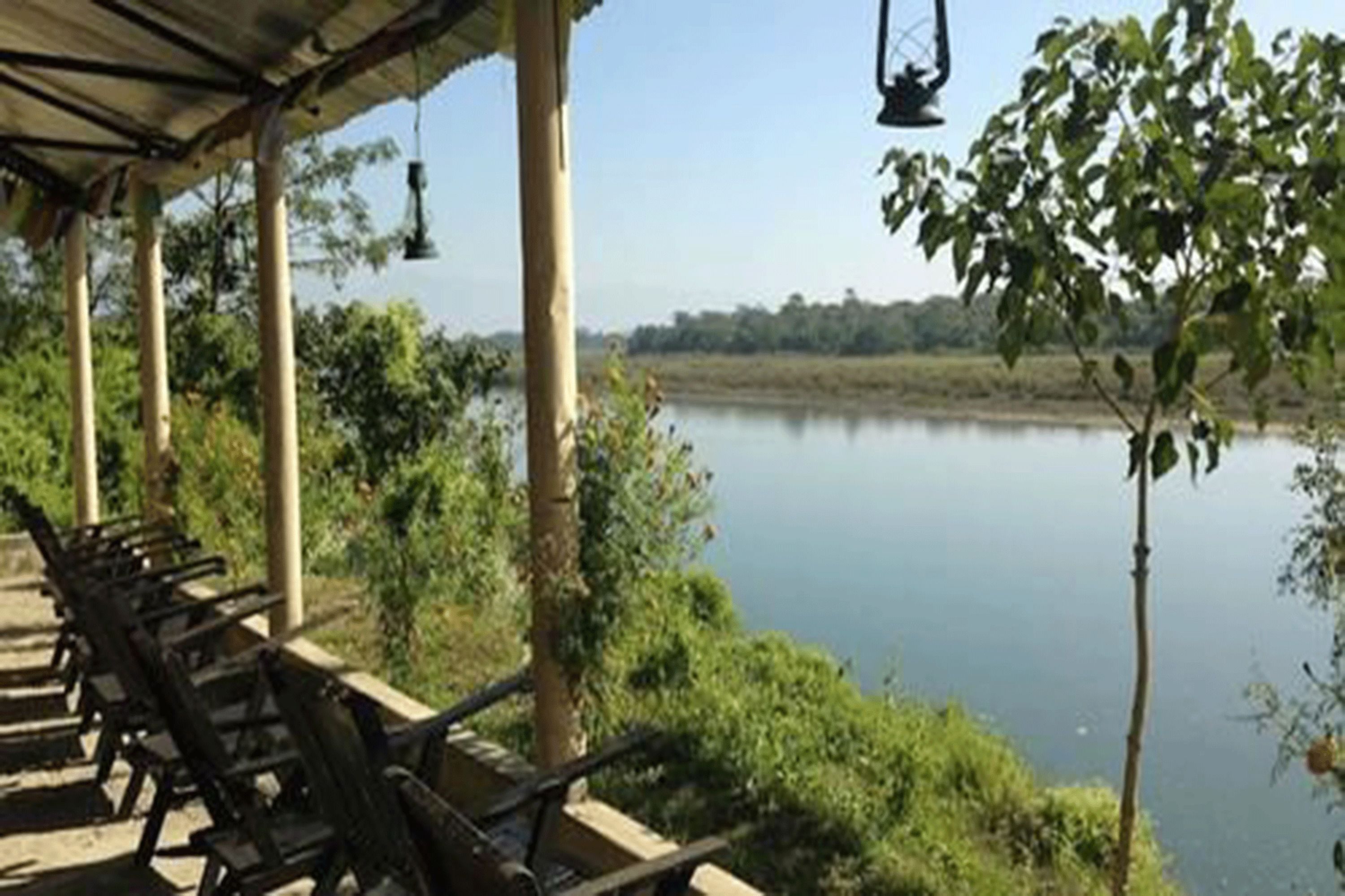 A covered outdoor seating area with chairs and a view of a calm lake.