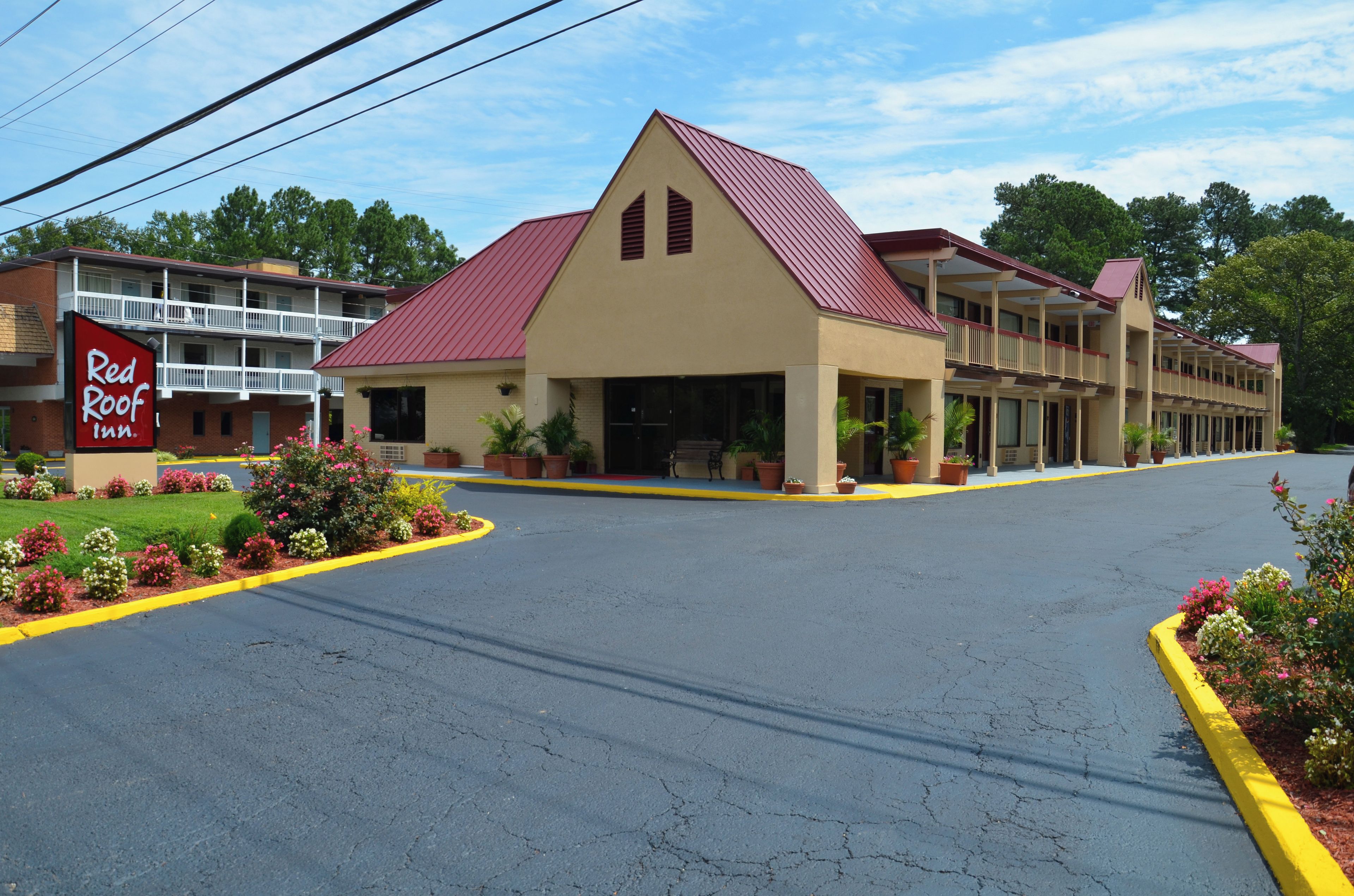 Un Red Roof Inn con techo rojo, una construcción de dos pisos y un estacionamiento.