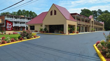 Un Red Roof Inn con techo rojo, una construcción de dos pisos y un estacionamiento.