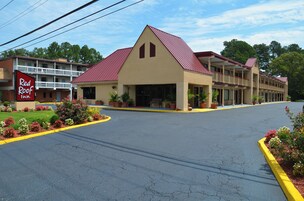 Un Red Roof Inn con techo rojo, una construcción de dos pisos y un estacionamiento.
