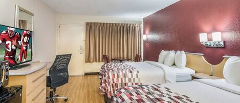 A hotel room with two beds, a desk with a television, a chair, and a window with curtains.