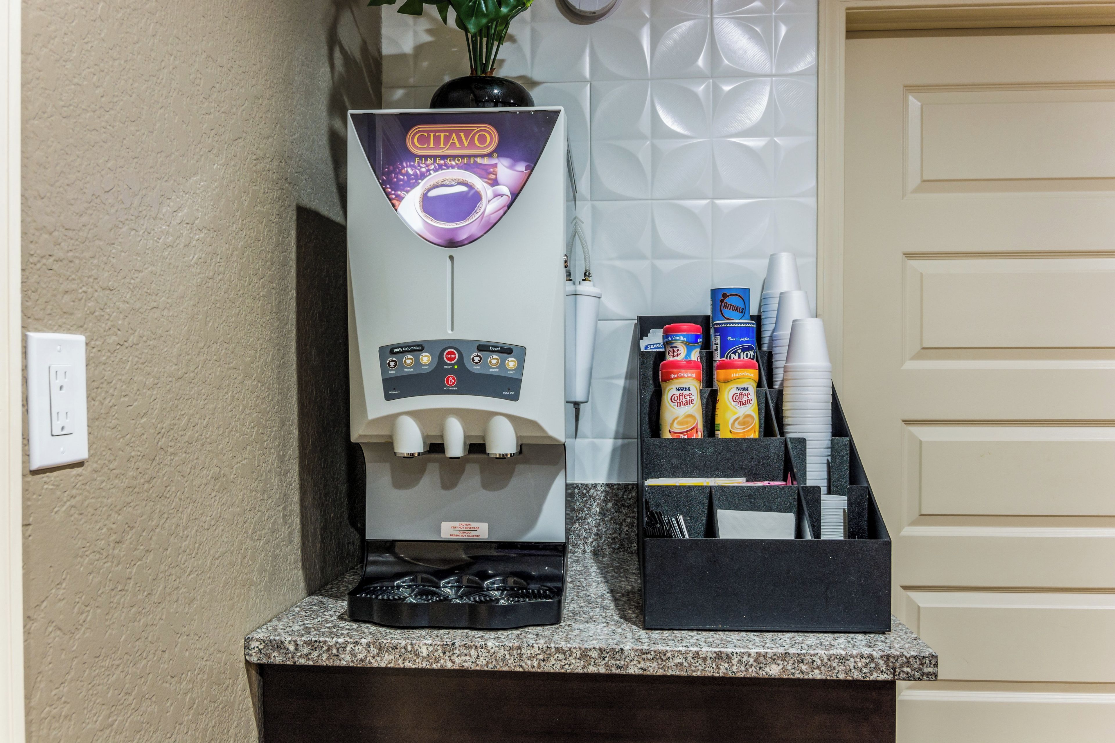 En kaffemaskine med kontrolpanel og kaffedispenser på en bordplade.