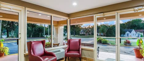 A room with two leather chairs, a large window, and a view of a residential area.
