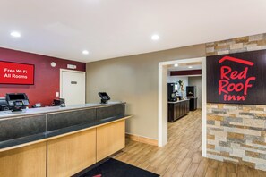 A hotel reception area with a counter, a private room sign, a Red Roof Inn sign, and a view into the kitchen. - Red Roof Inn Williamsburg (Williamsburg)