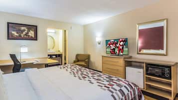 A hotel room with a bed, a desk, a chair, a television, and a microwave.